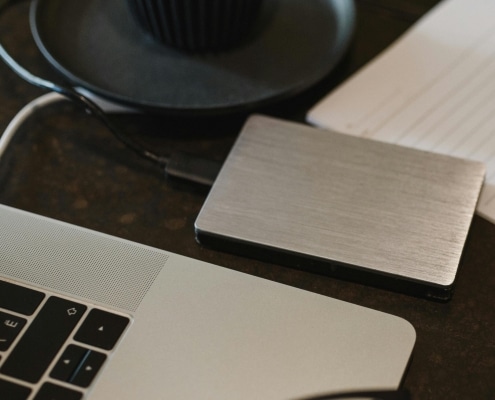 Free Closeup of an external hard drive connected to a laptop with a USB cable on a desk. Stock Photo