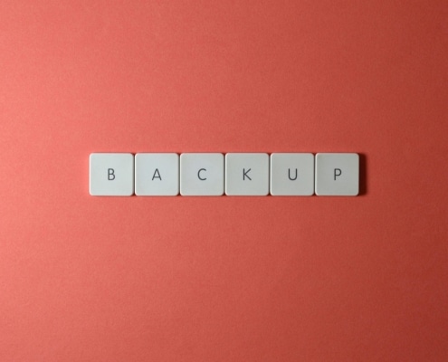 Free Close-up of keyboard keys spelling 'BACKUP' placed on a coral-colored surface. Stock Photo